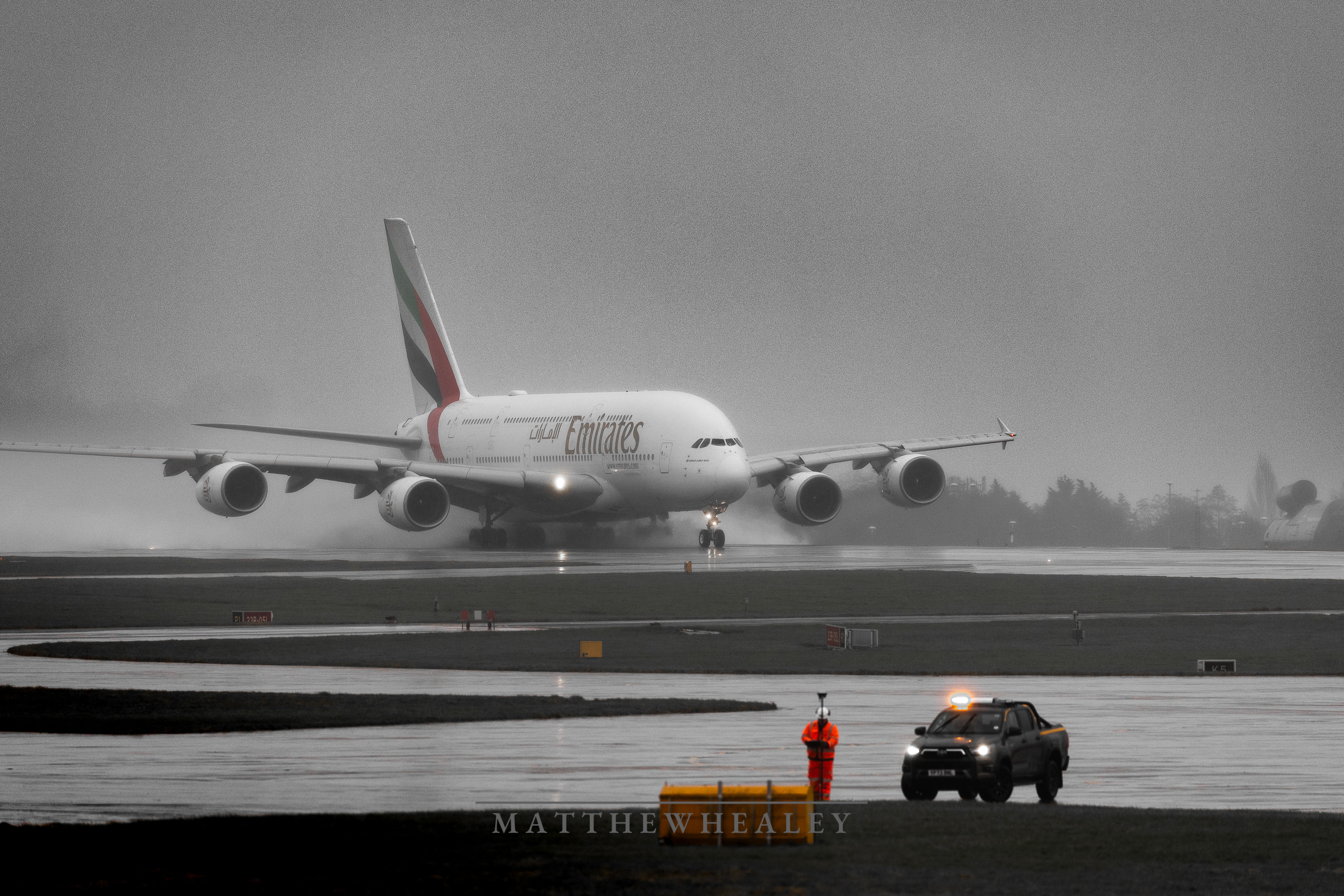 An image of a large Emirites plane in the rain creating a mist which creates a moody muted photo.